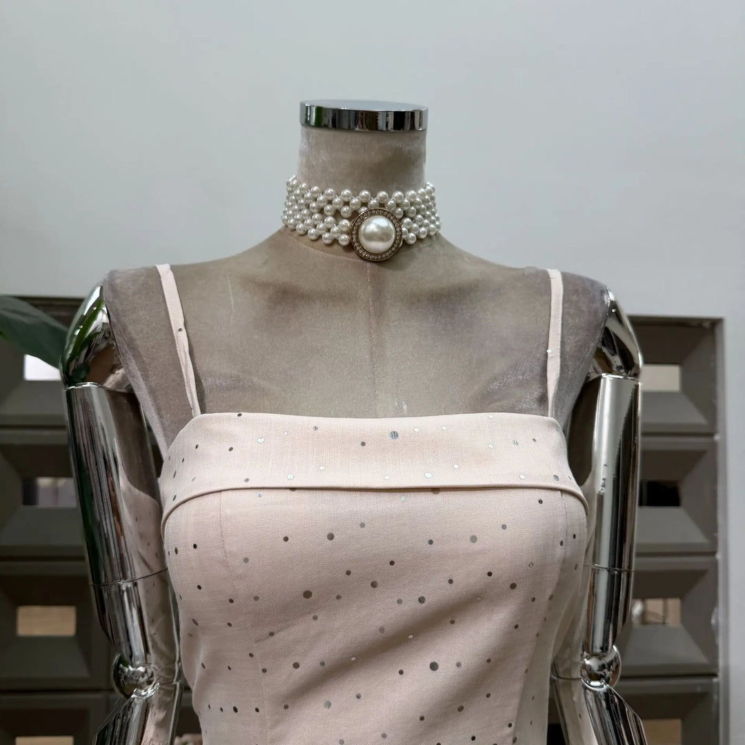 Beige polka dot mini dress on mannequin, pearl-look collar with round center clasp