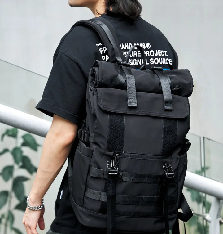 Black roll-top travel rucksack with front flap pockets and adjustable shoulder straps