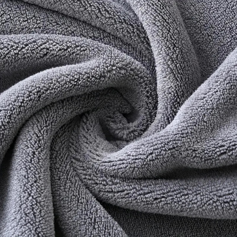 Plush velvet bath towel fabric close-up in gray, showing dense soft texture.