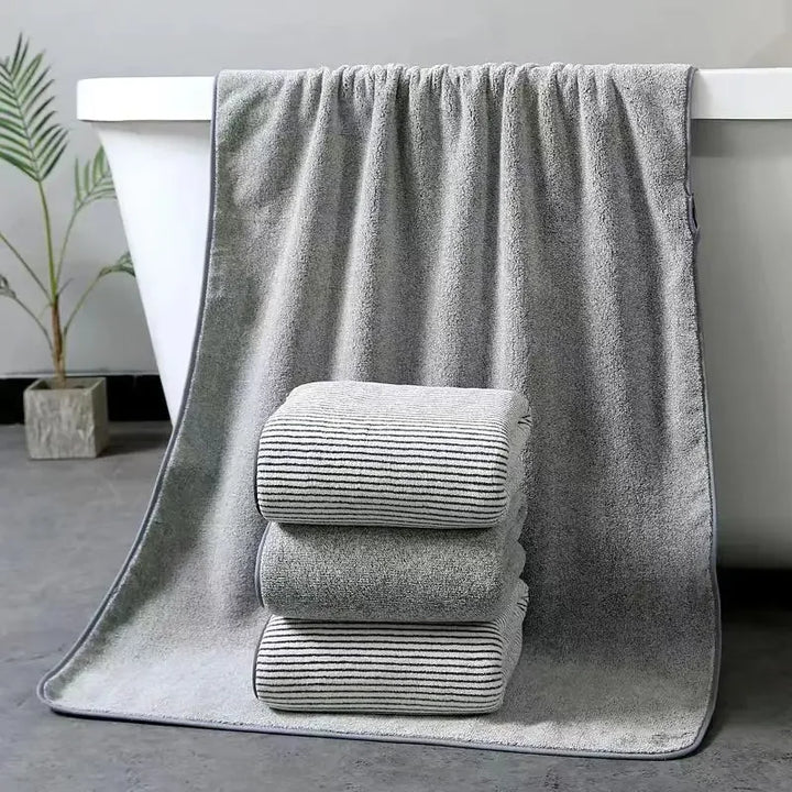 Gray towel set: two folded striped towels resting on a plush bath towel