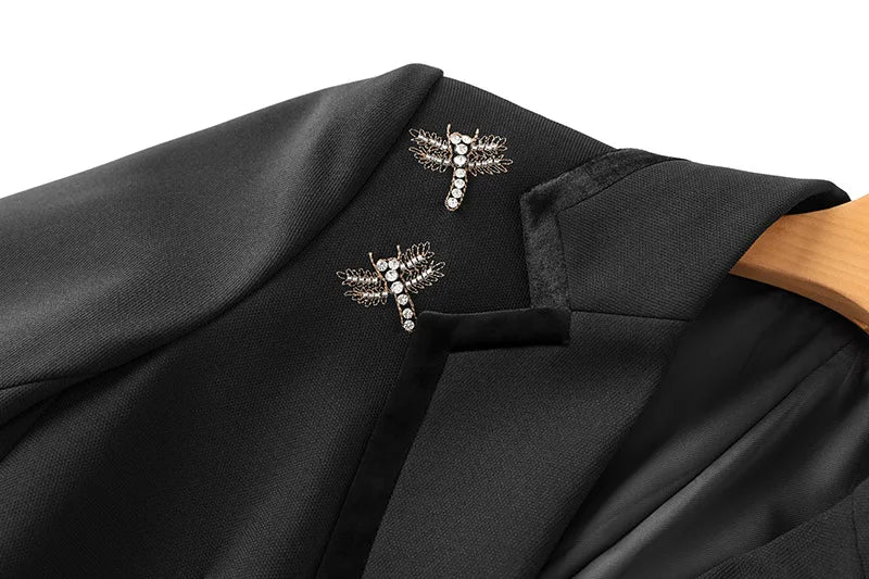 Black blazer lapel close-up with two cross brooch-style rhinestone embellishments