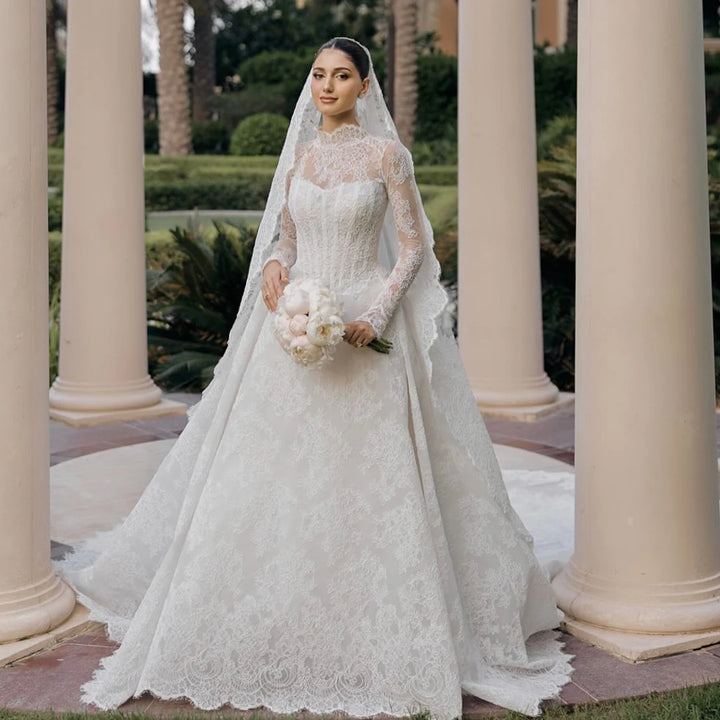 White lace high-neck wedding gown with long sleeves and flowing tulle veil