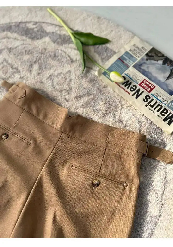 Khaki beige flat-front dress pants close-up: waistband button, belt loops, and front pleats.