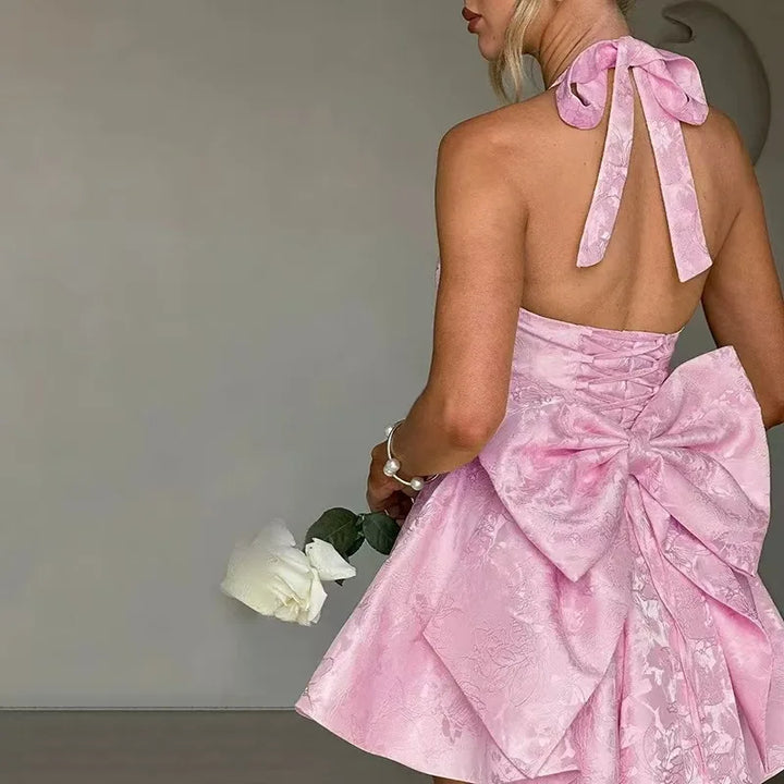 Light pink mini A-line dress back view with halter tie bow and floral textured skirt