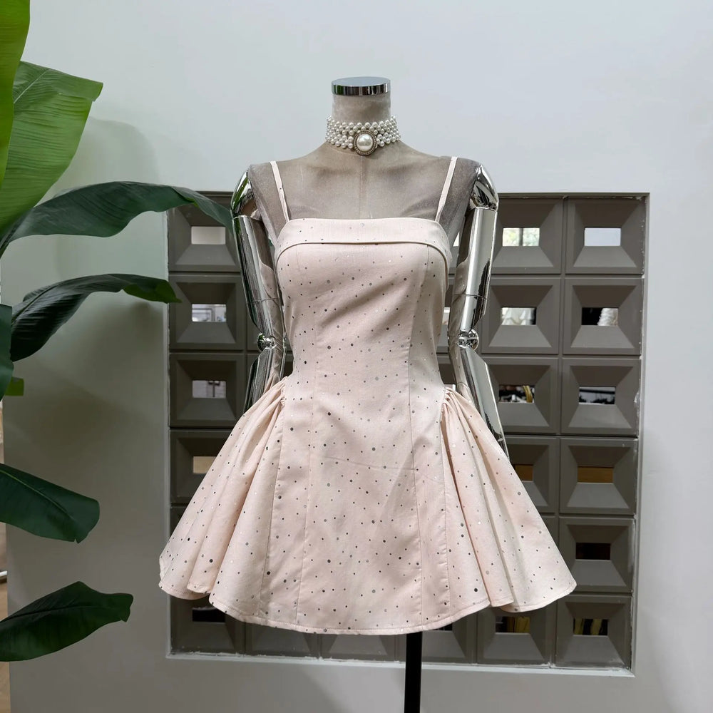 Beige polka dot mini dress on mannequin with pearl choker detail and flared skirt