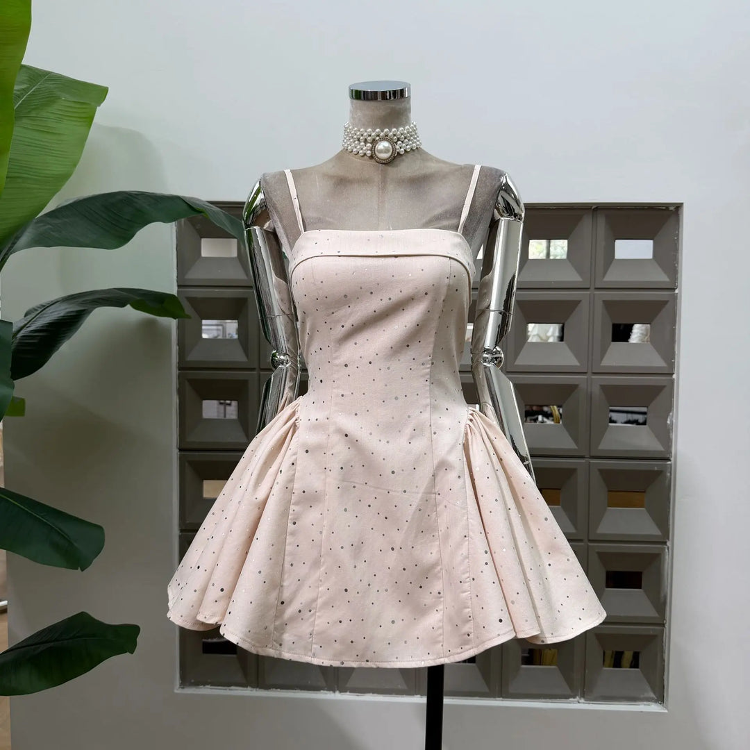 Beige polka dot mini dress on mannequin with pearl choker detail and flared skirt