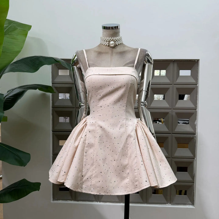 Beige polka dot mini dress on mannequin with pearl choker detail and flared skirt