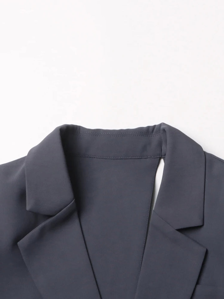 Charcoal-gray blazer shoulder with structured notch collar and inner cutout panel