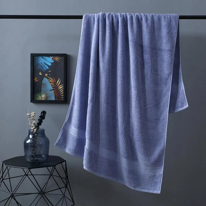 Bath towel in light blue, hanging with textured terry surface and hem detail