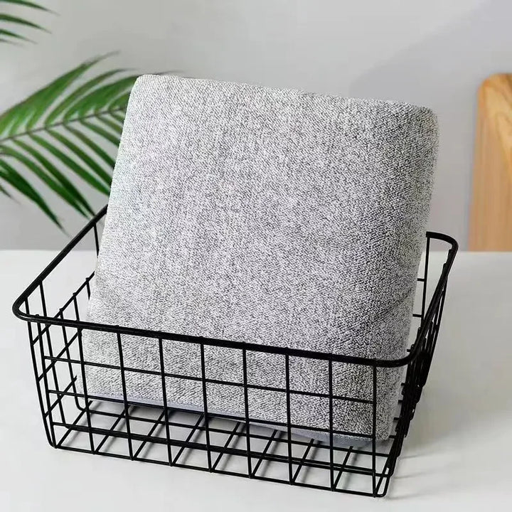Heather gray face towel folded and placed in a black wire basket
