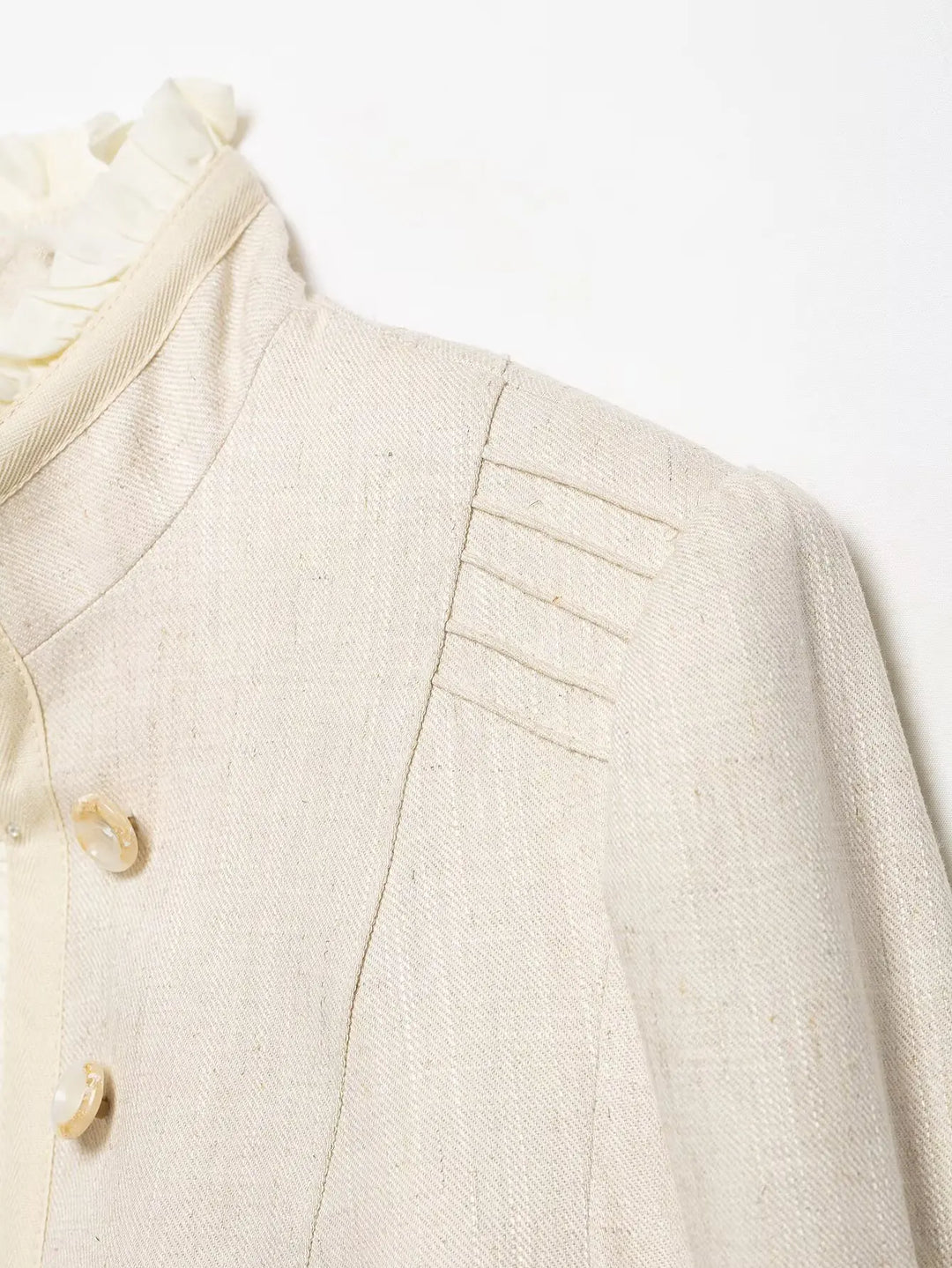 Beige cropped blazer shoulder and lapel detail with button closure