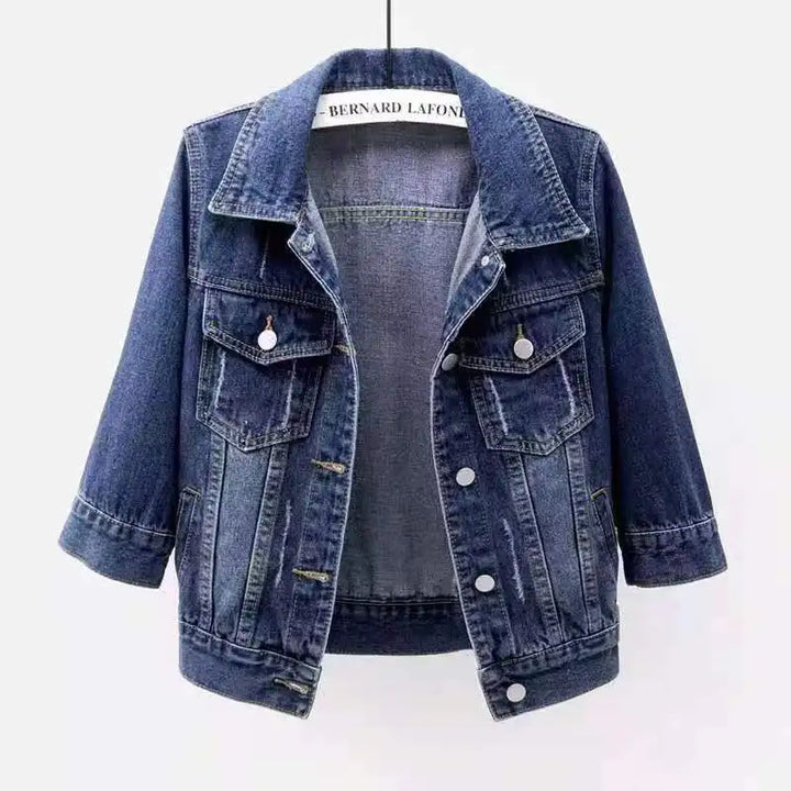 Blue denim jacket with three-quarter sleeves, flap chest pockets, and button front