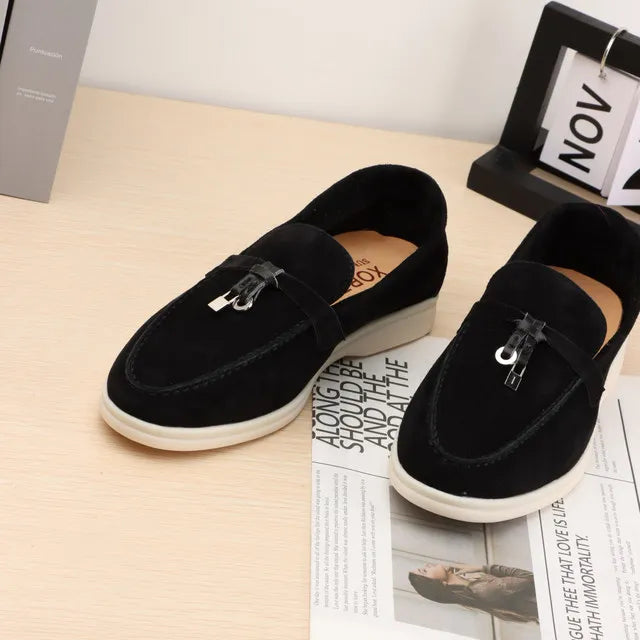 Black suede slip-on loafers with metal buckle and moc toe stitching