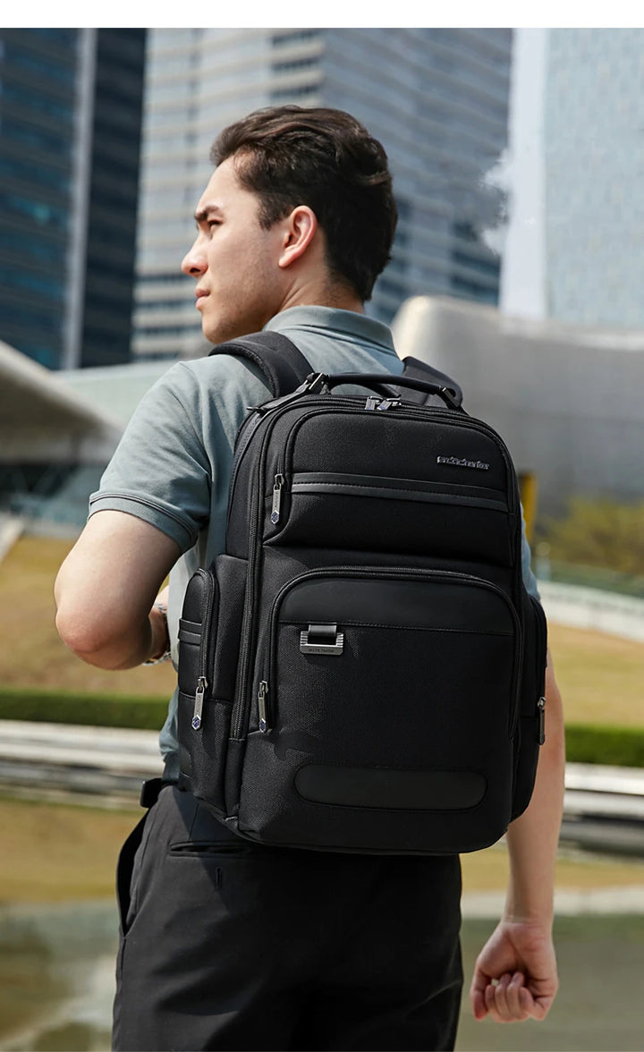 Black backpack worn by a man with front compartments and padded shoulder straps