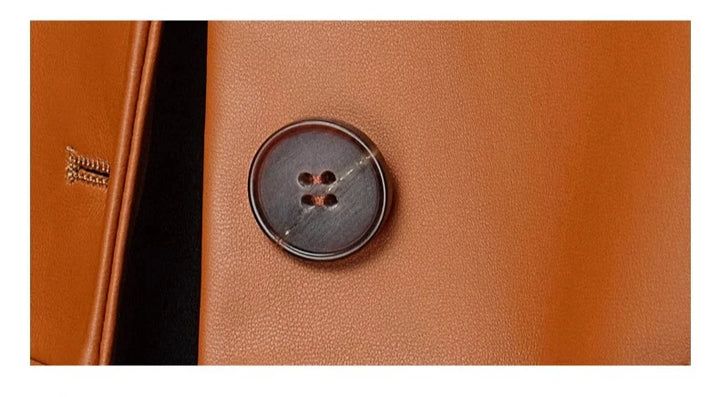 Women’s sheepskin woven coat close-up of round dark button on orange leather