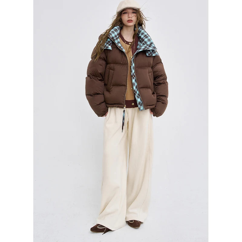 Brown hooded puffer jacket with teal plaid hood and front zip over light pants