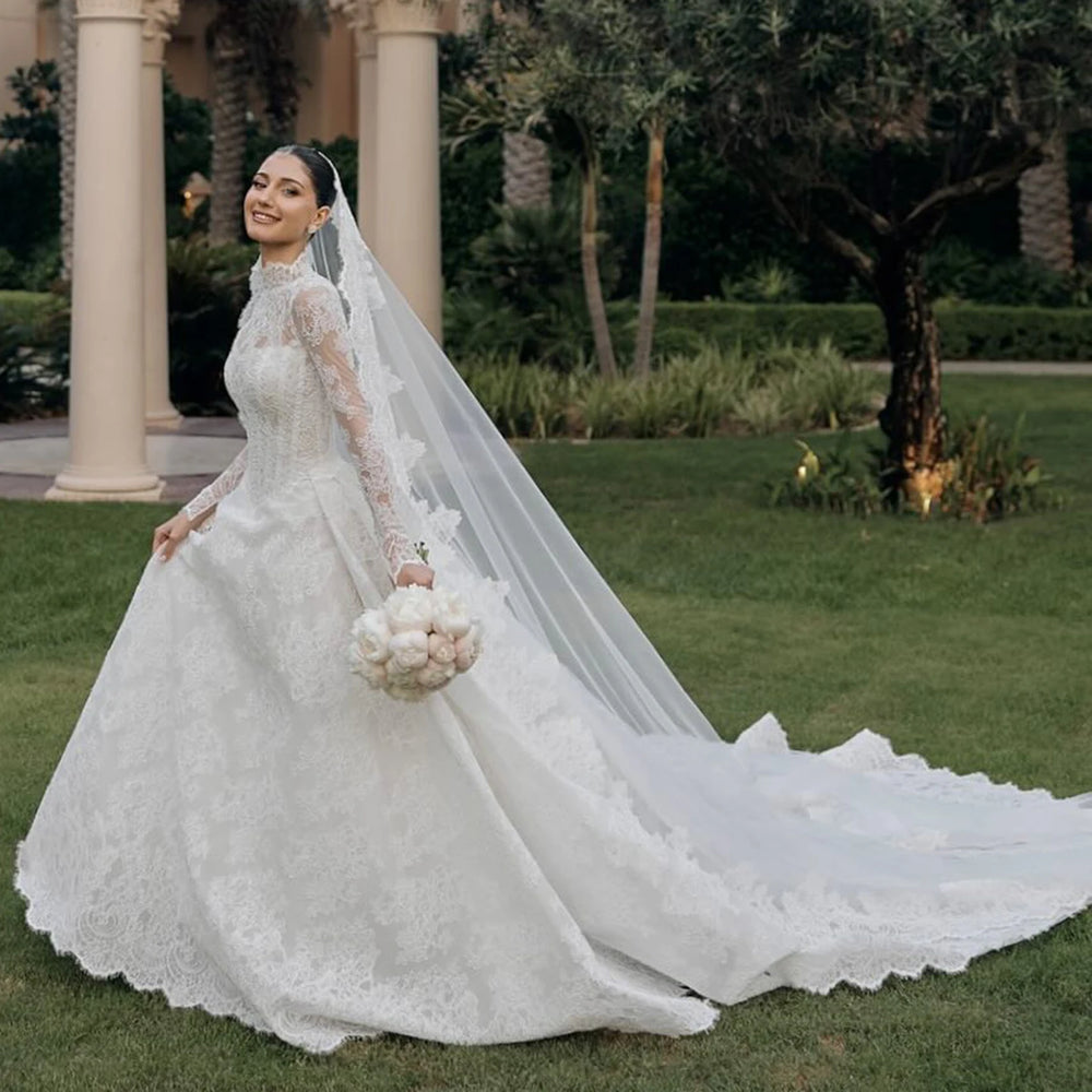 White lace high-neck wedding gown with long sleeves, full skirt, and sheer veil