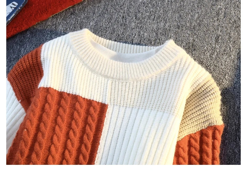 Patchwork knit sweater closeup with orange cable panel, white stripes, and cream/gray blocks.