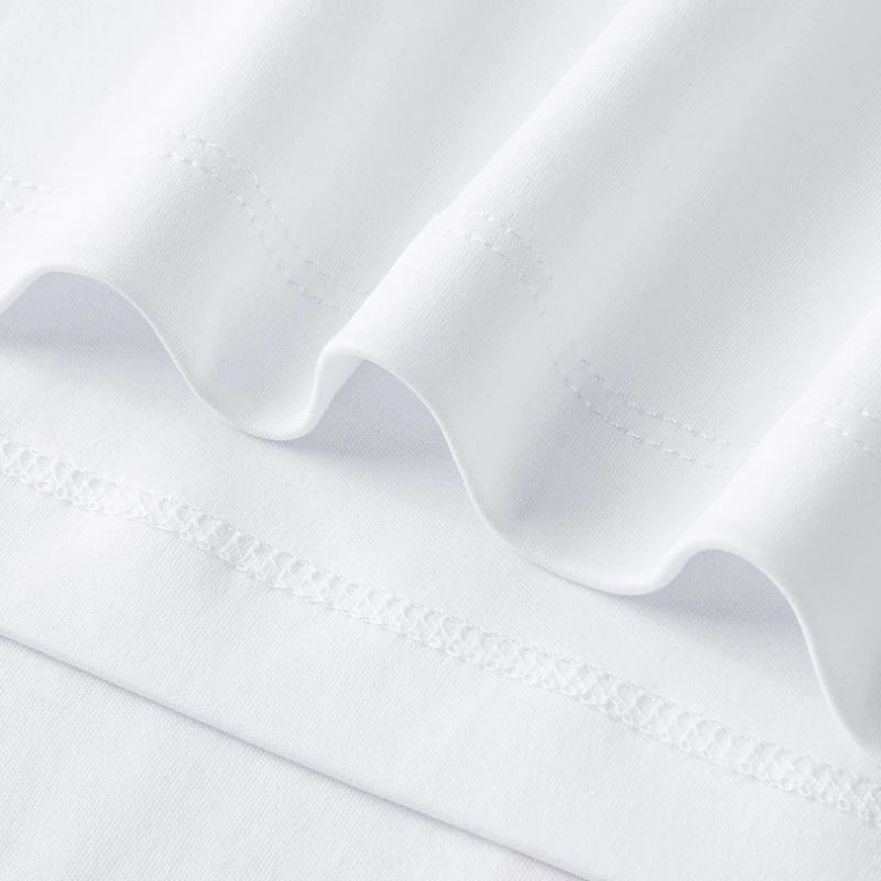White crew-neck tee fabric close-up with stitched hem and seam details