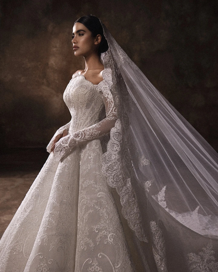 White lace boat-neck bridal gown, fitted bodice, long sleeves, side view with veil