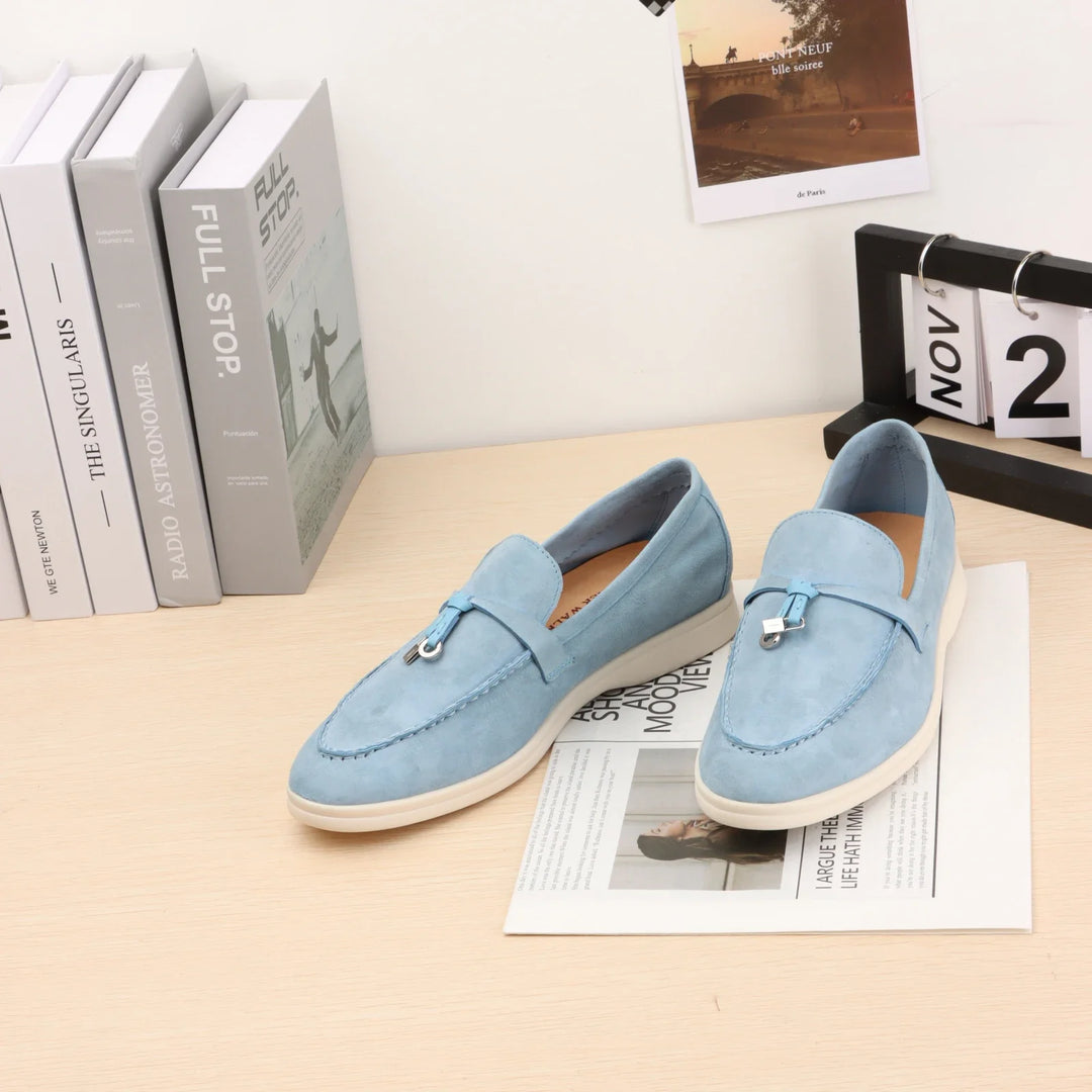 Light blue suede slip-on loafers with metal bit detail and white rubber sole.