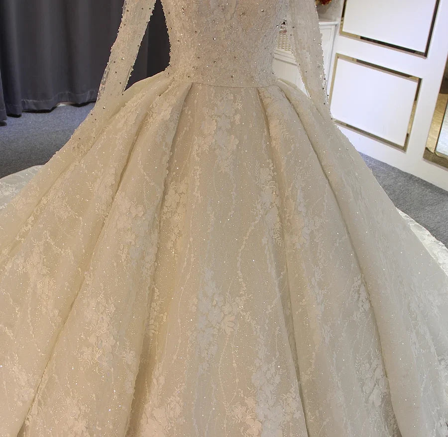 Close-up of lace bride dress bodice with fitted lace sleeves and sparkling applique