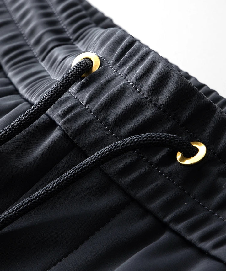 Navy jogger pants waistband with black drawstring and gold-tipped eyelets