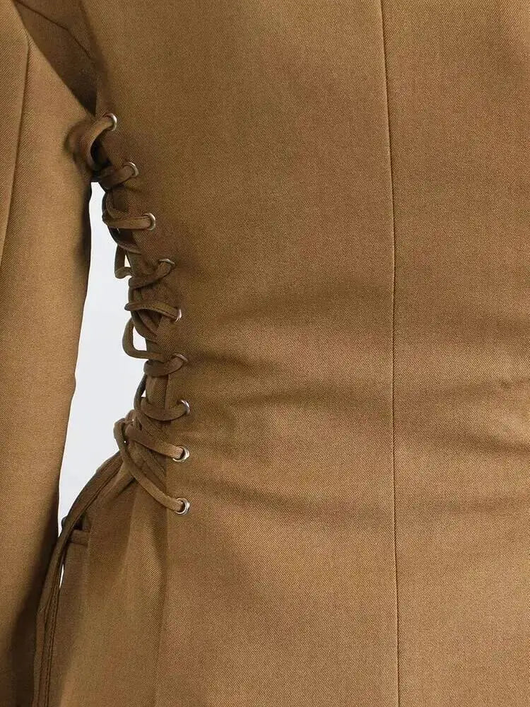 Brown blazer front close-up with lace-up sleeve grommets and tailored seams