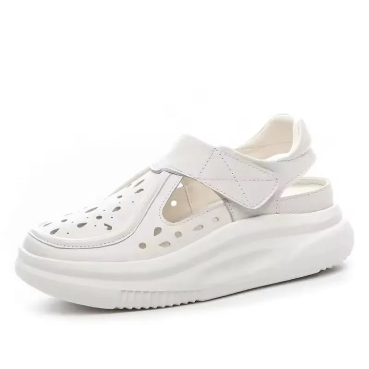 White thick-sole leather sandals with perforations, open sides, and wide platform sole.