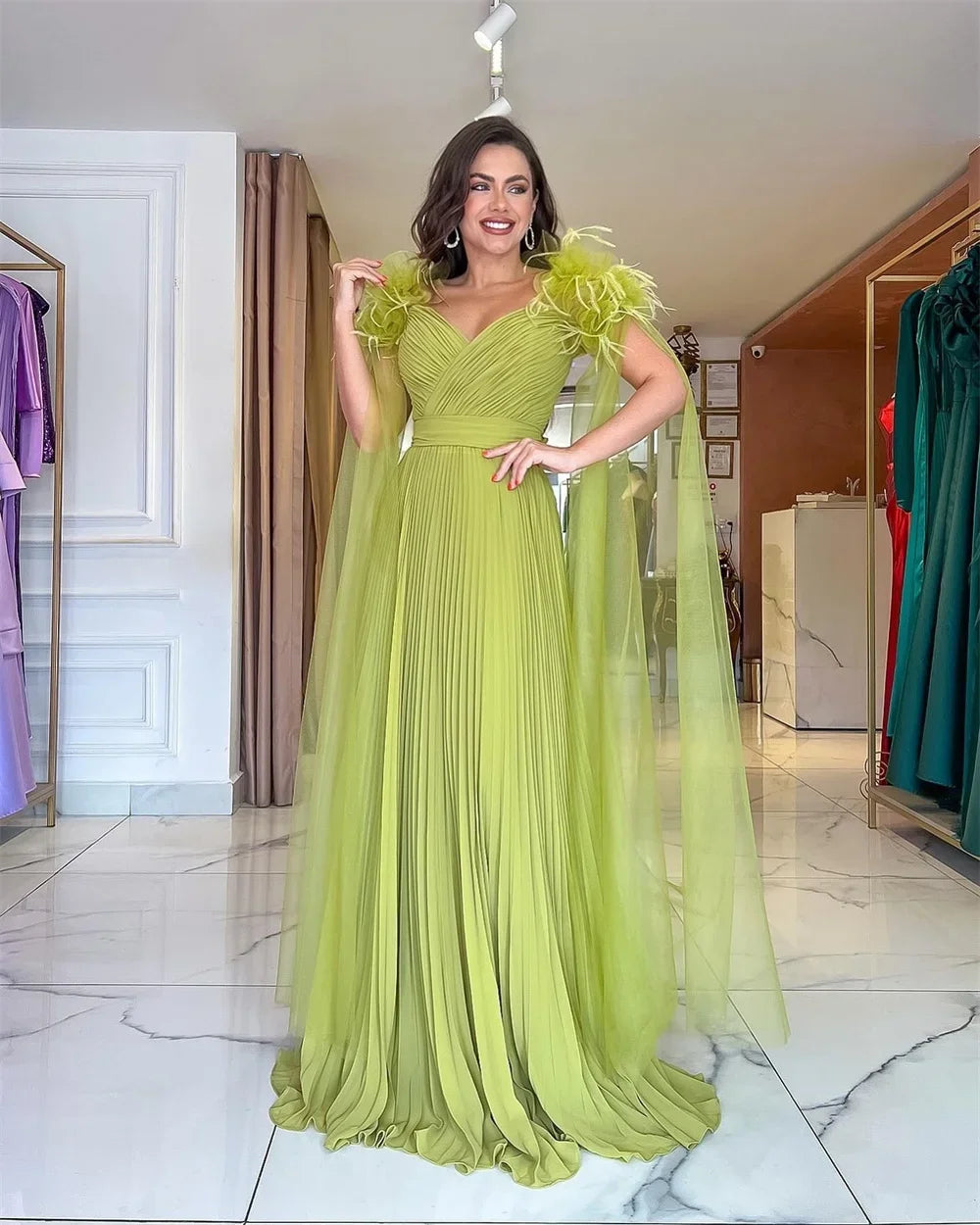 Light green formal gown front view with V-neck, pleated skirt, and feathered shoulder accents