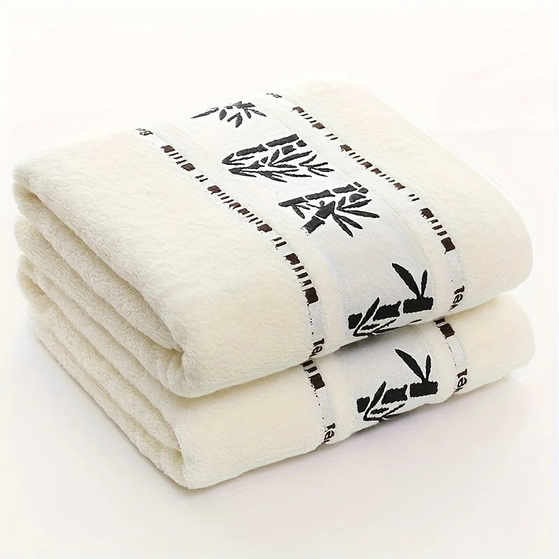 Stacked white towels with black bamboo-pattern border