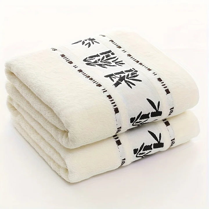 Stacked white towels with black bamboo-pattern border