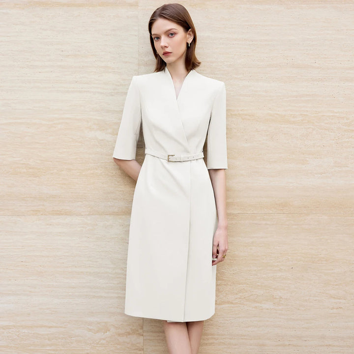Beige knee-length skirt suit with V-neck, waist belt, and short sleeves.