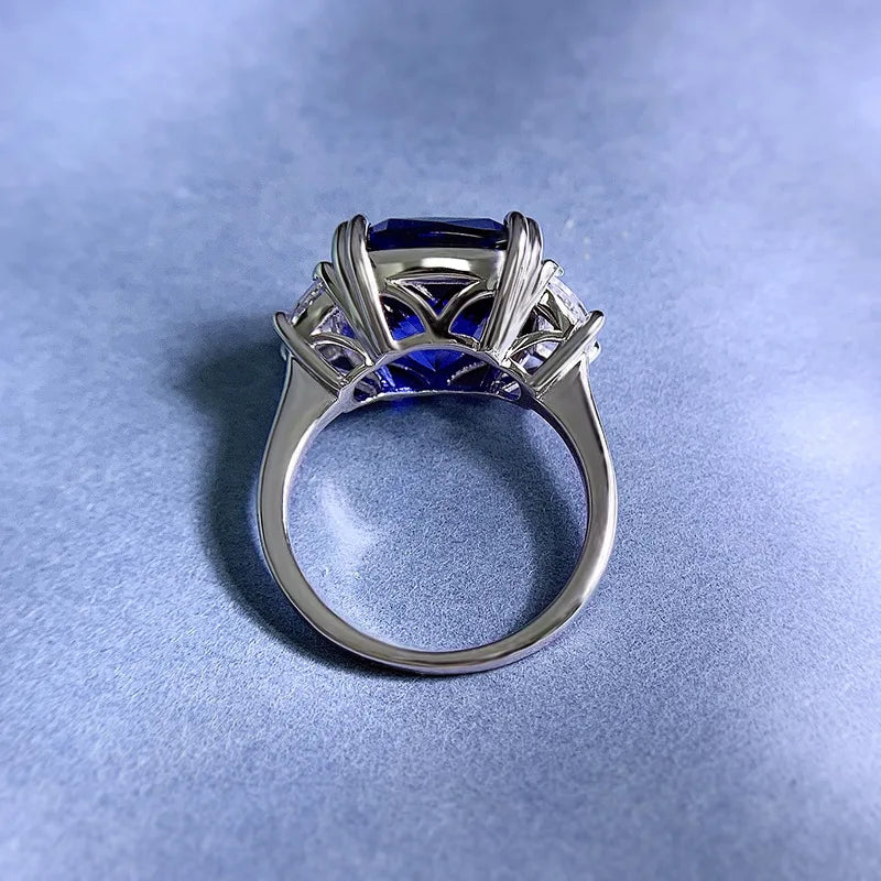 Sterling silver ring with openwork prongs around blue center stone and clear side gems
