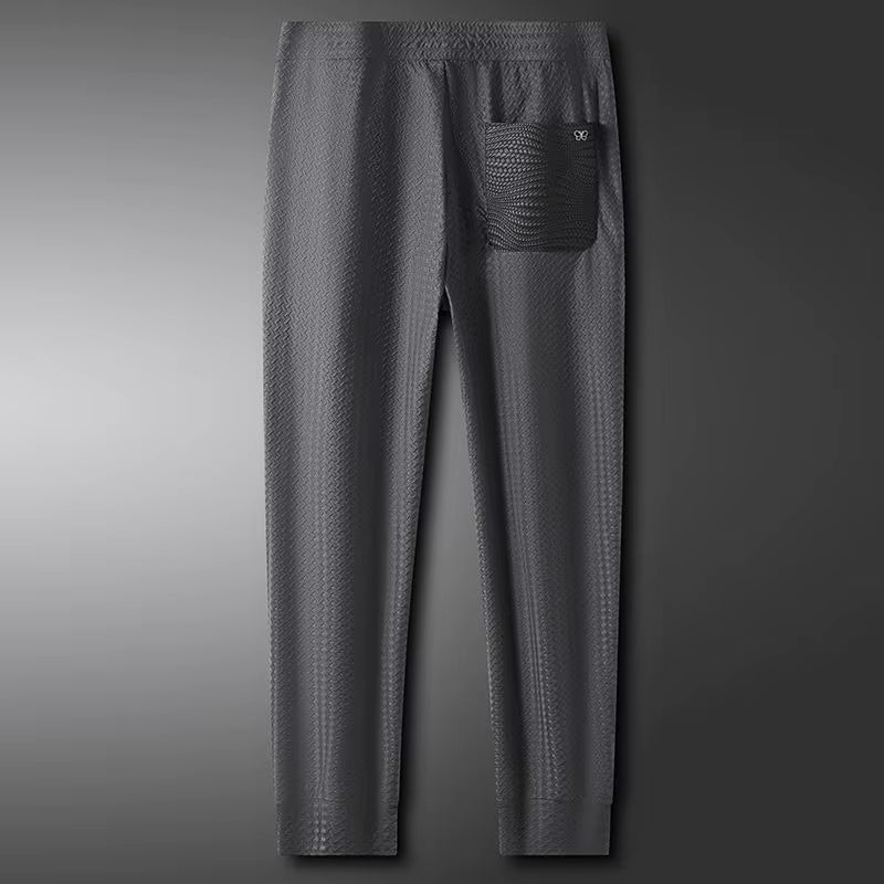 Grey textured slim-fit trousers with drawstring waist and tapered legs