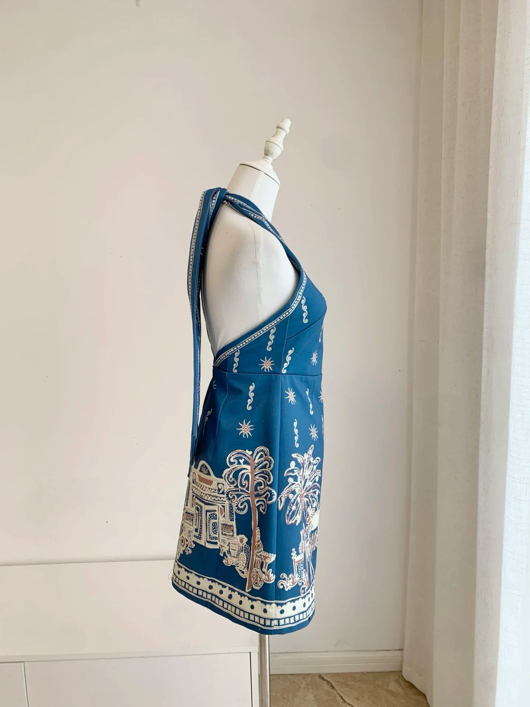 Blue halter neck mini dress side view, sleeveless with decorative border print