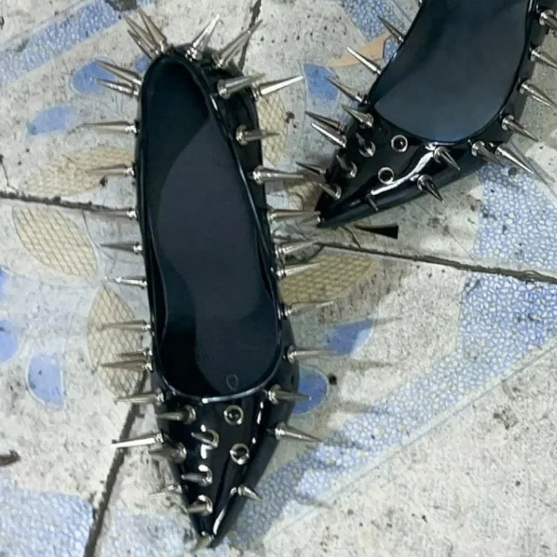 Black patent leather pointed-toe heel pumps with silver spike rivets on side and toe