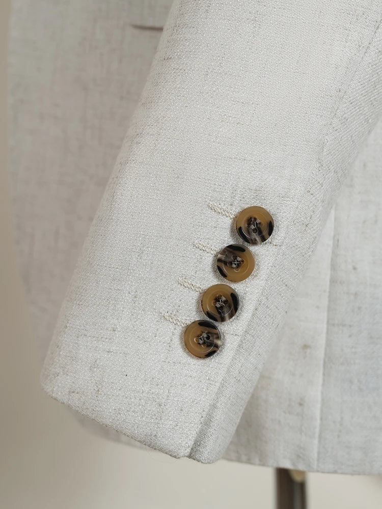 Close-up of light beige suit jacket cuff with three round brown buttons