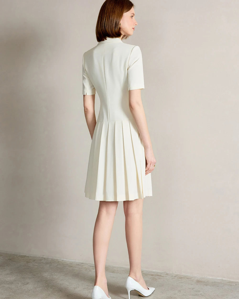 Back view of beige A-line dress with short sleeves and pleated skirt