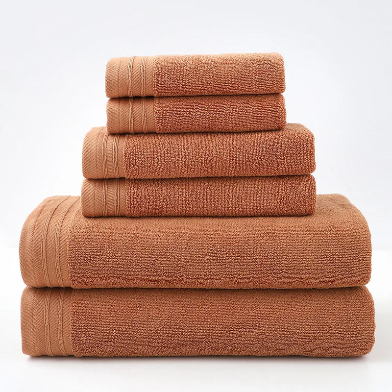 Rust-colored cotton bath towel set, stacked rolled towels with solid terry texture