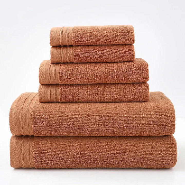 Rust-colored cotton bath towel set, stacked rolled towels with solid terry texture
