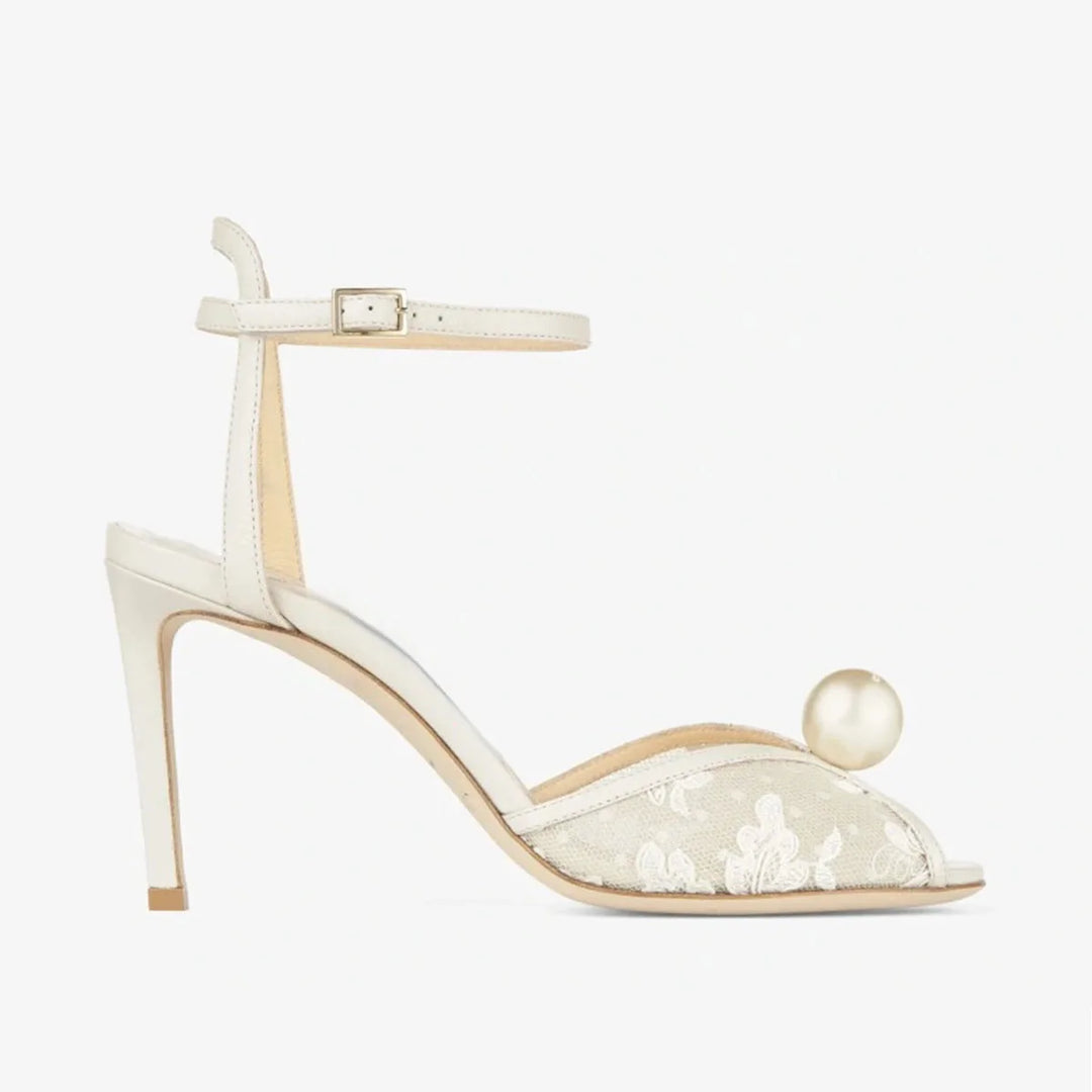White high heel sandal with ankle strap, peep-toe lace, and large pearl on toe