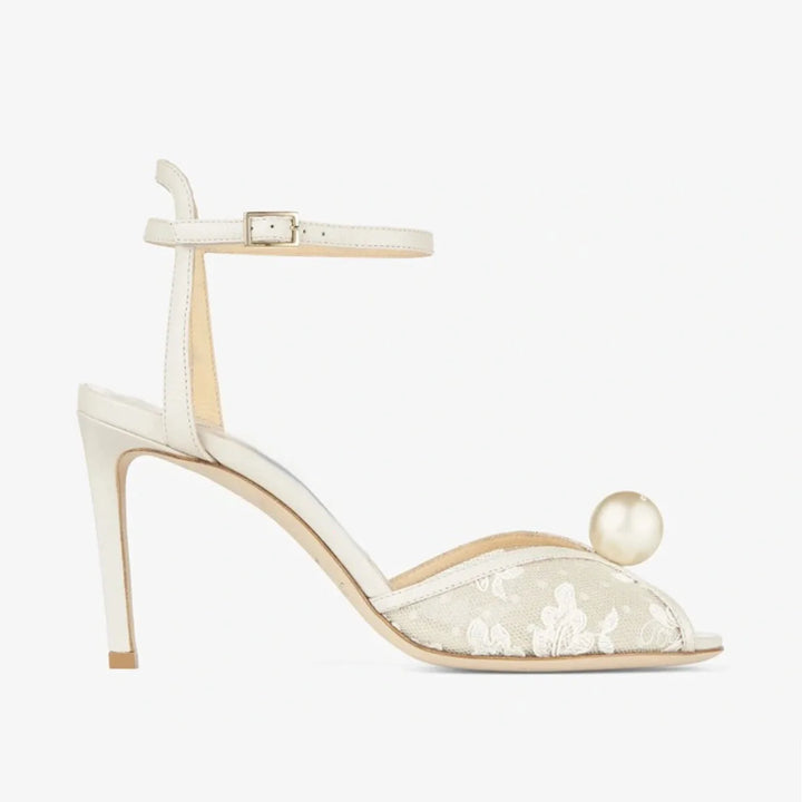 White high heel sandal with ankle strap, peep-toe lace, and large pearl on toe