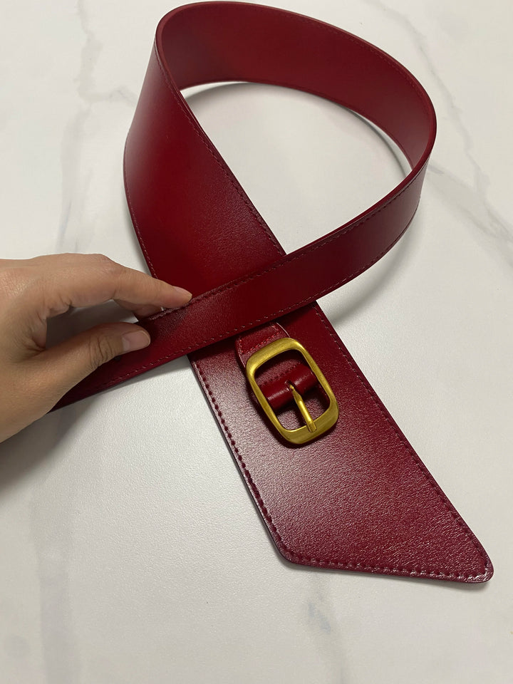 Red leather corset belt detail with gold buckle and stitched triangular strap tip