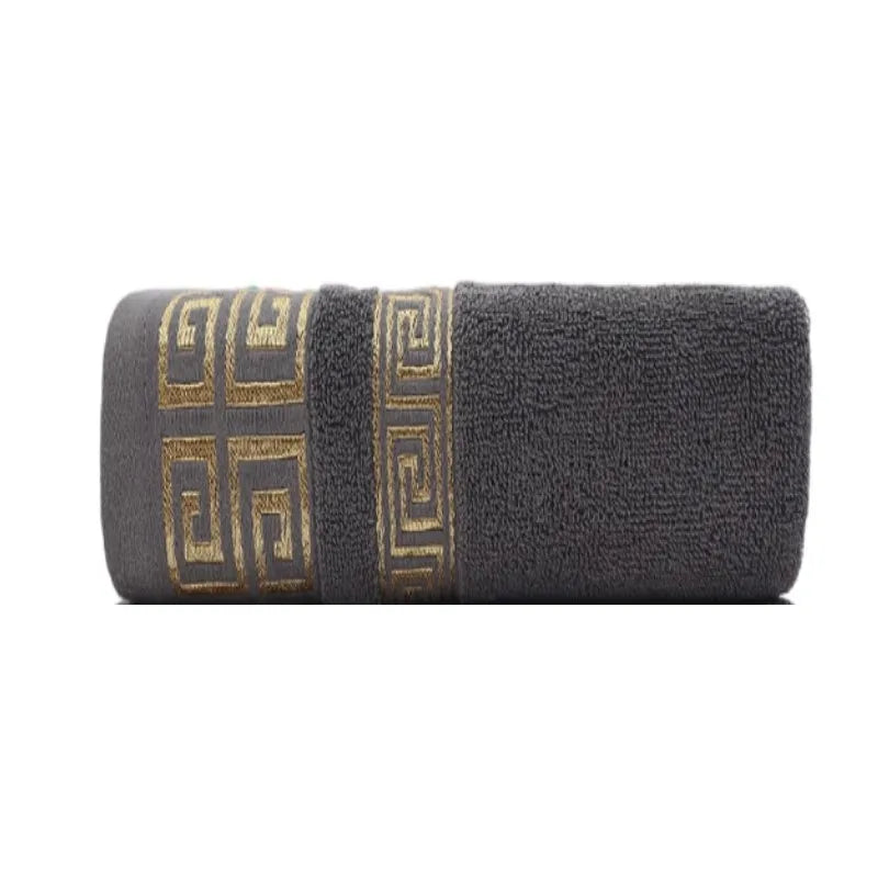 Cotton bathroom towel set in dark gray with gold Greek border, rolled.