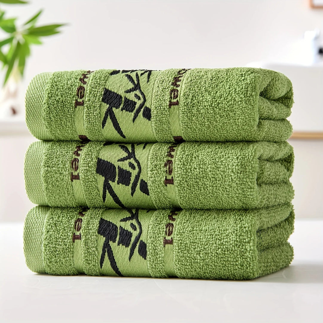 Stack of cotton bathroom towels in green with black bamboo print borders