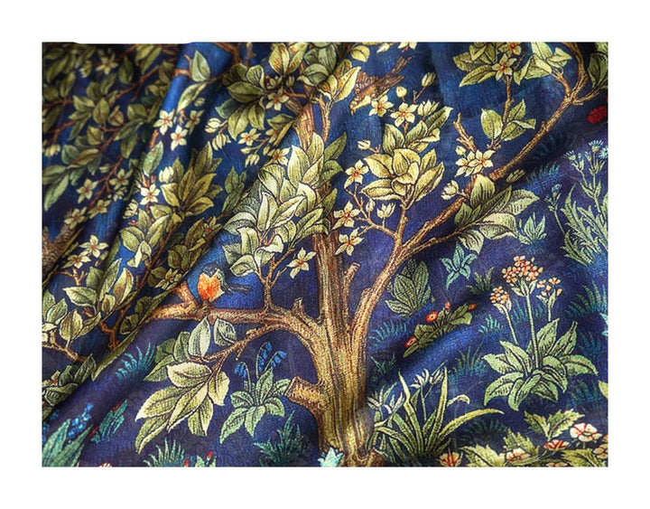 Fabric with intricate tree and floral pattern on a blue background, branded 'Fimtairah'.