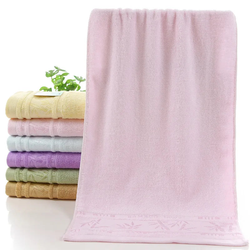 Bamboo towel set with a front blush-pink towel; other stacked towels in cream, light blue, and lavender.