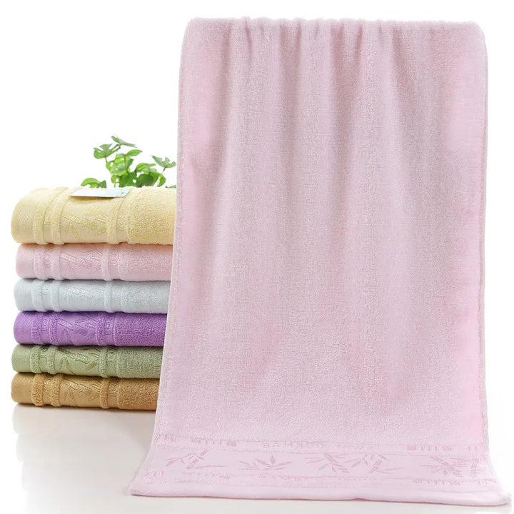 Bamboo towel set with a front blush-pink towel; other stacked towels in cream, light blue, and lavender.