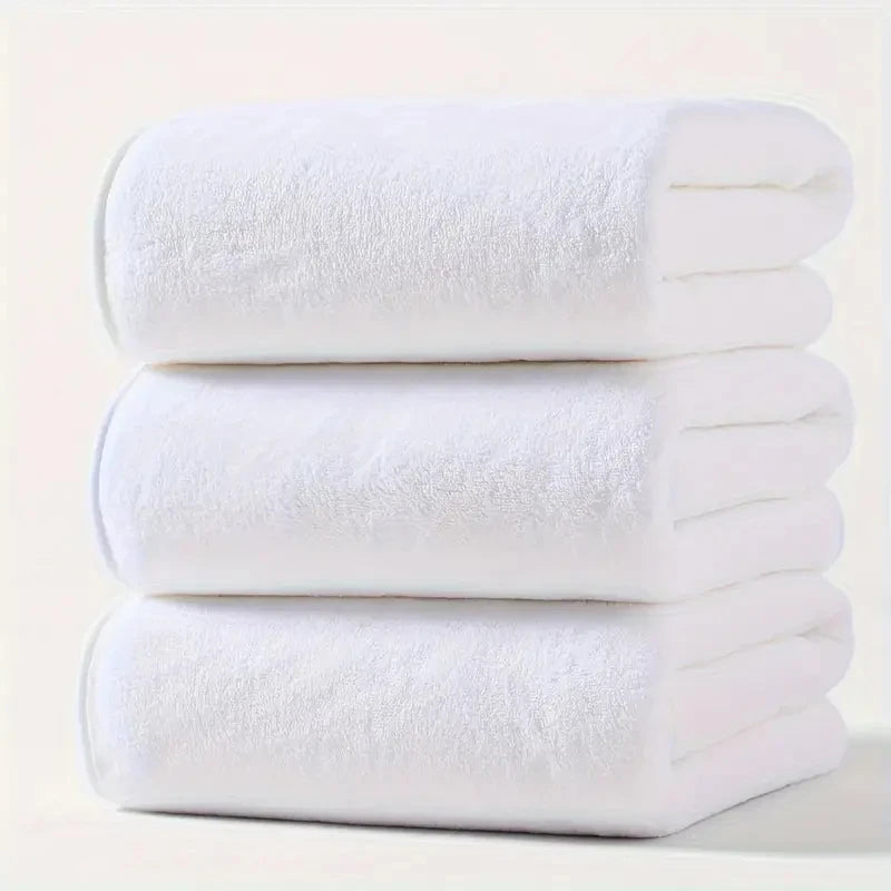 Plush velvet bath towel set in white, three folded towels stacked.